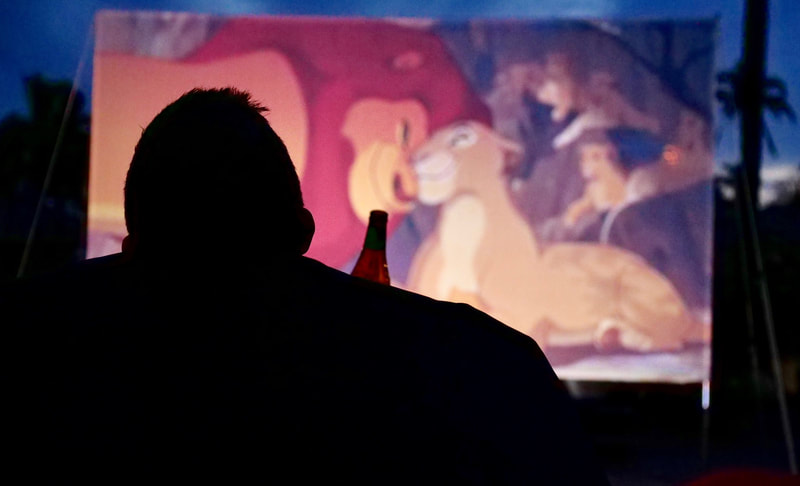 silhouette of a man reclining in a bean bag with a beer while watching the Lion King on an outdoor cinema hired in Perth.