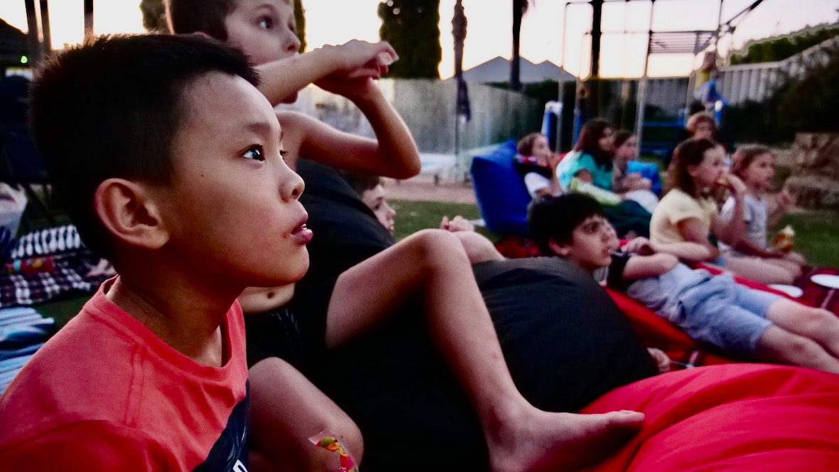 Children watching an outdoor cinema movie.
